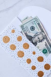 gift envelope with heap of greenbacks on marble table